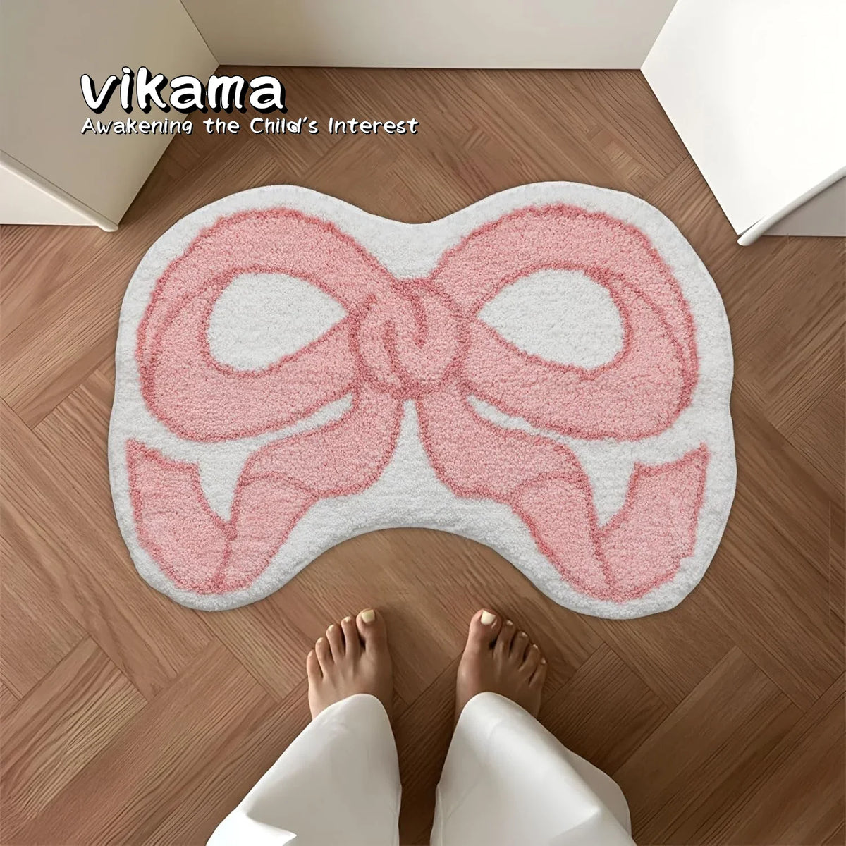 A pink bow-shaped absorbent non-slip doormat placed on a wooden floor.