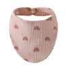 A light pink organic cotton muslin baby bib with a textured surface and a rounded shape.
