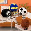 A collection of realistic sports ball plush toys including a football, basketball, volleyball, and an eight-ball resting on a