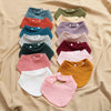 A collection of colorful organic cotton muslin baby bibs in various shades including blue, green, pink, and yellow.
