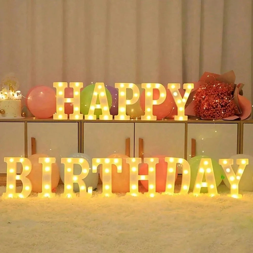 LED letter night lights spelling HAPPY BIRTHDAY arranged on a table with colorful balloons and glitter