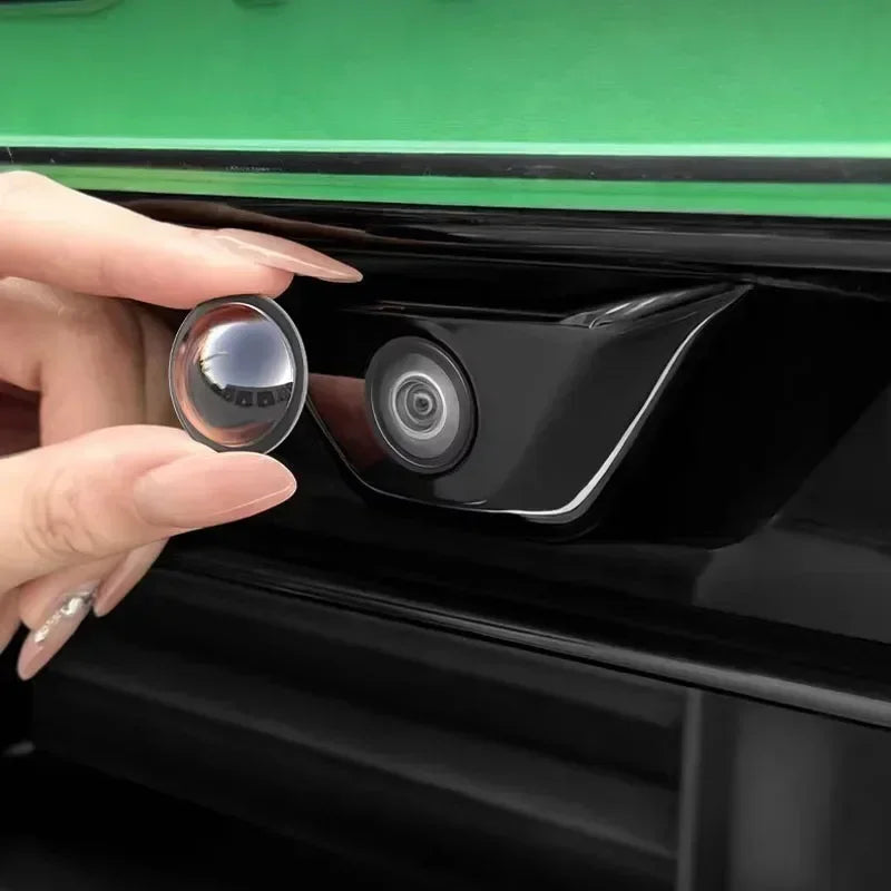 A hand is opening a black device, revealing a camera lens and protective cover.