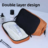 An open orange toiletry bag with a black lining, showing a white brush and a small bottle inside.