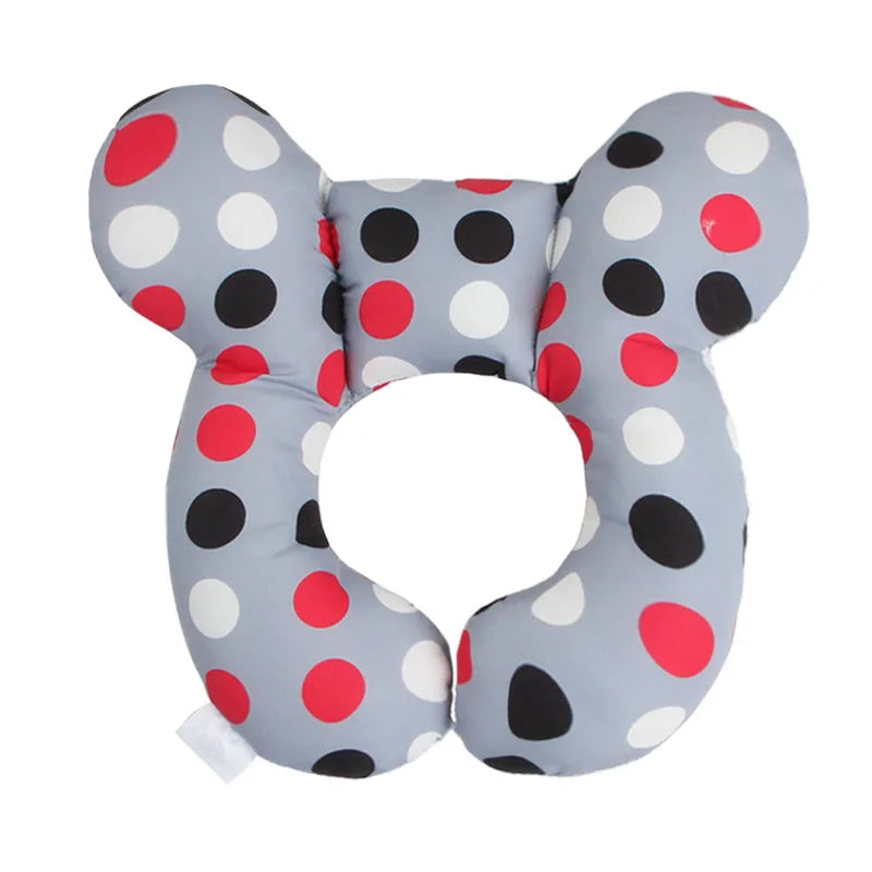 A gray baby head and neck support pillow with red and black polka dots.