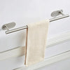 A stainless steel towel bar with a beige textured towel hanging on a white wall.