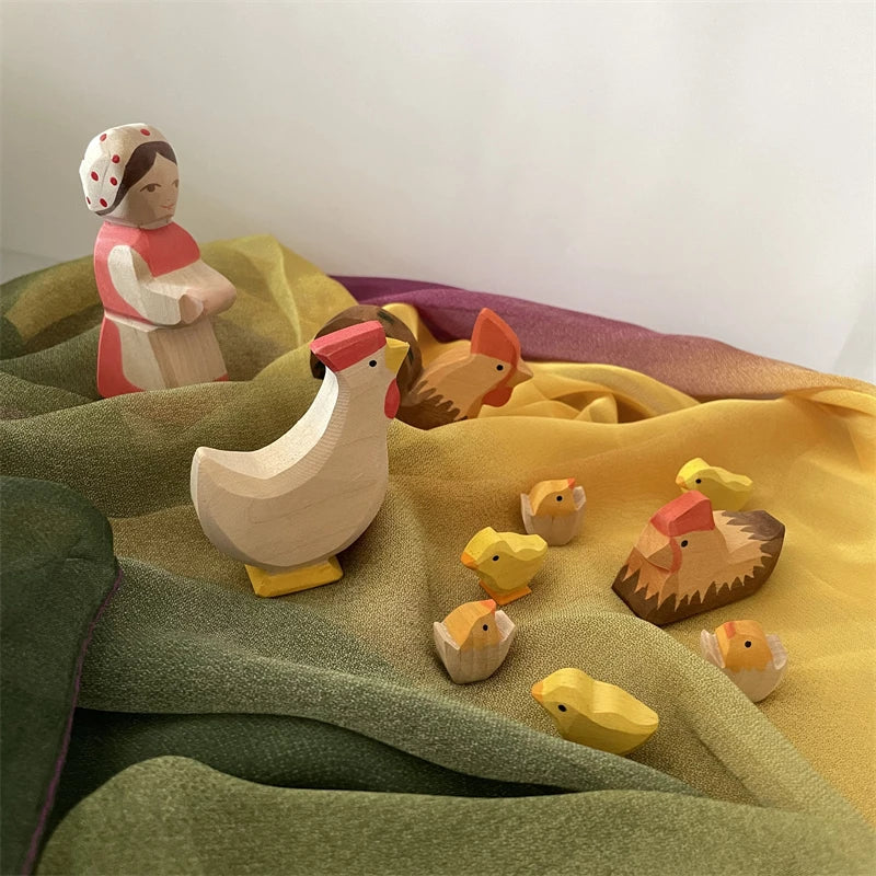 Wooden Montessori playsilks of various animals, including a bird and a rabbit, displayed on green fabric.