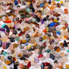 A close-up view of mixed natural crystal gravel stones and gemstone chips in various colors like pink, purple, blue, and ambe
