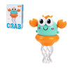 An orange crab toy with large eyes and dancing legs is shown next to its packaging box.
