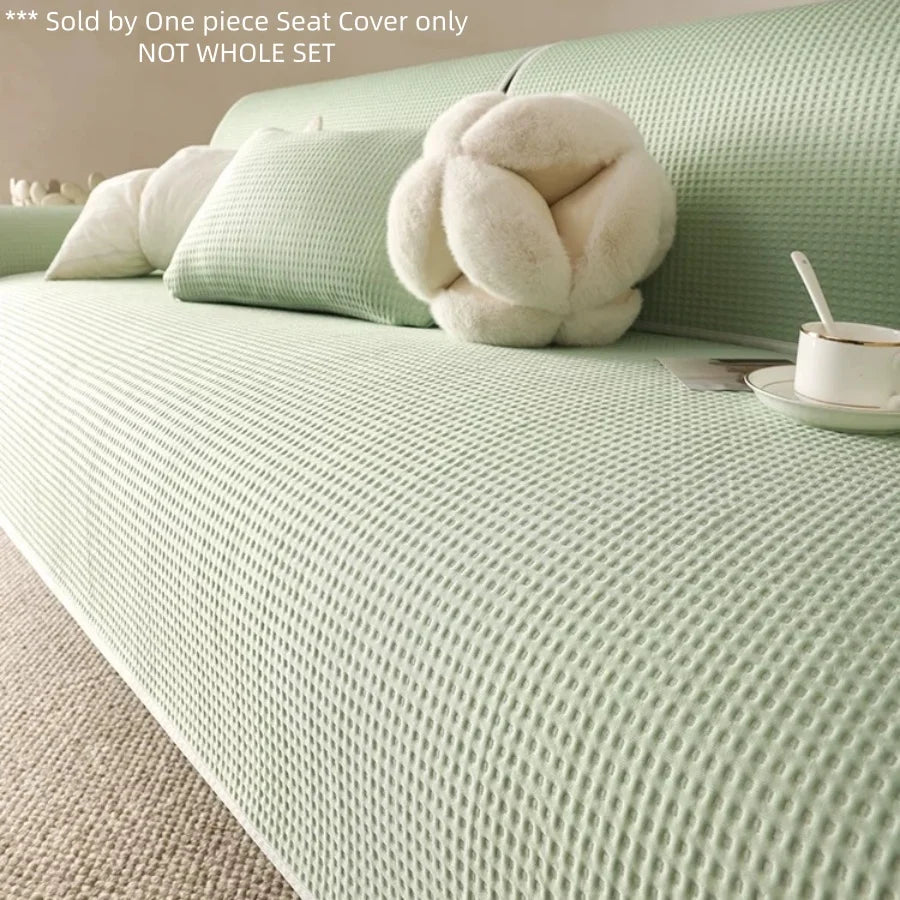 Helles grün Anti-Rutsch-Sommersofa-Überzug auf einem Bett mit flauschigen weißen Kissen.