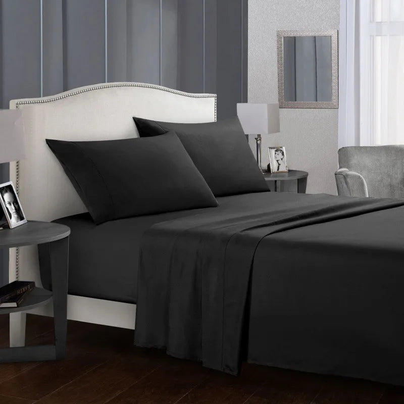 Un lit gris foncé avec tête de lit et literie blanche dans une chambre moderne.