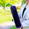 A hand holds a purple 32-key melodica with a white mouthpiece and case in an outdoor setting.