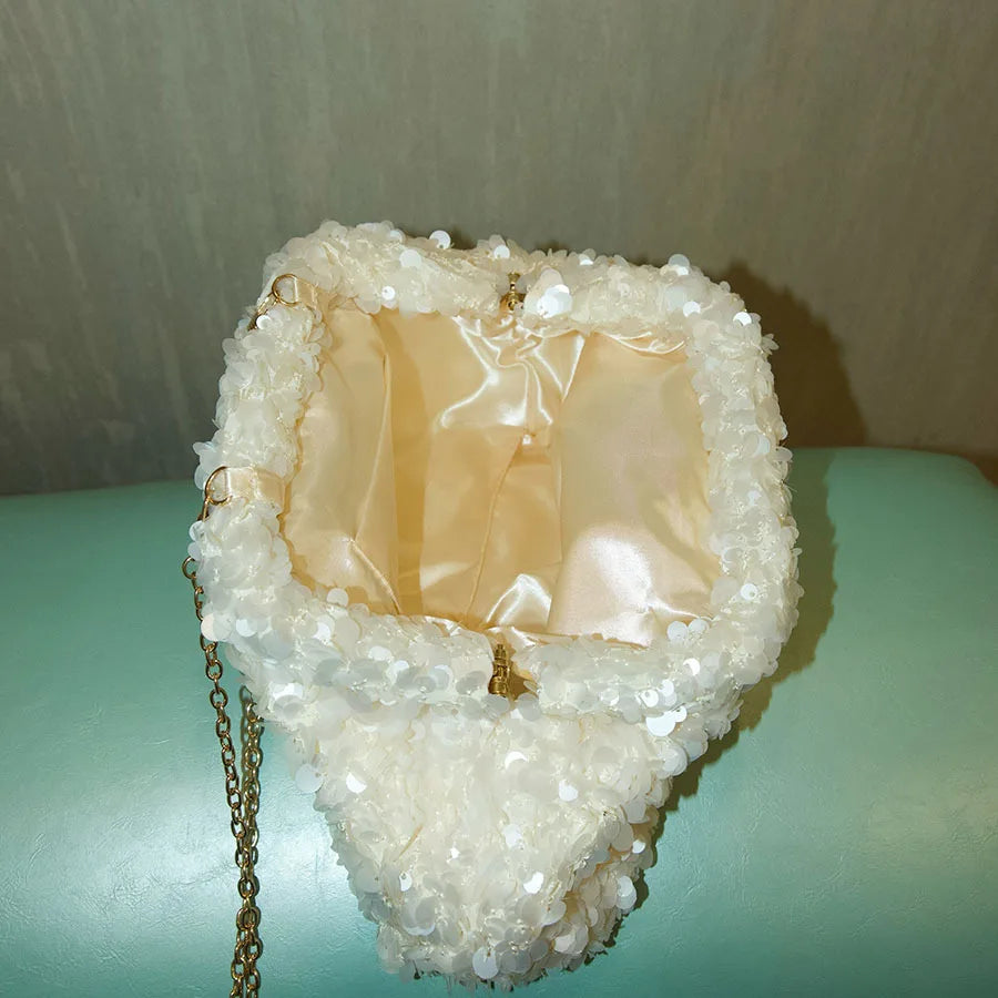 A white sequin beaded chain shoulder clutch bag with a light pink lining and gold chain detail.