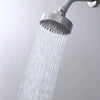 A matte black shower head is spraying a strong stream of water from a modern chrome faucet onto a white wall.