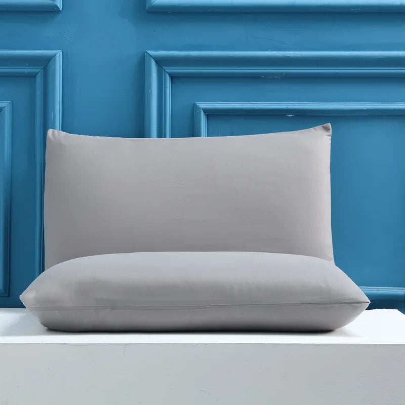A light gray rectangular pillow and a matching cylindrical pillow are displayed against a blue paneled wall.