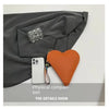 A heart-shaped orange PU coin purse with a wrist strap is shown next to a gray blazer sleeve for comparison.
