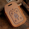 A brown leather key fob case with embossed symbols for Chevrolet and GMC vehicles resting on a wooden surface.