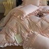 A pink ruffled duvet cover set with matching pillowcases and a decorative gold bedside table.