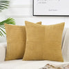 A set of two mustard yellow corduroy patchwork throw pillow covers displayed on a white sofa.