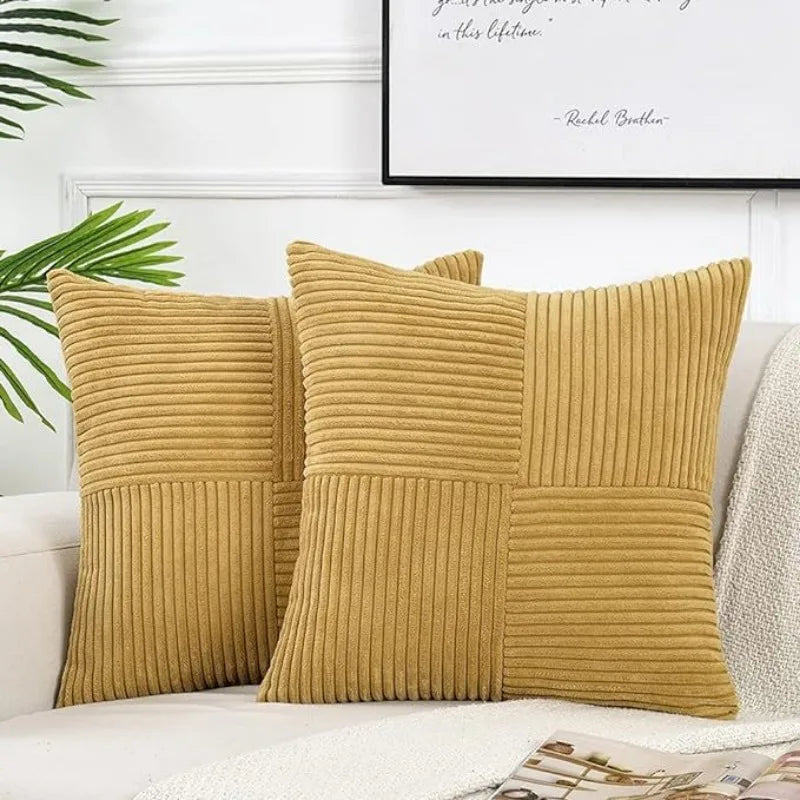 A set of two mustard yellow corduroy patchwork throw pillow covers displayed on a white sofa.