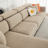 A beige jacquard elastic sofa slipcover with orange accent pillows on a light-colored sofa.