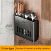 A black cutlery organizer with a 3-hole design holds various silverware and is mounted on a wooden surface.