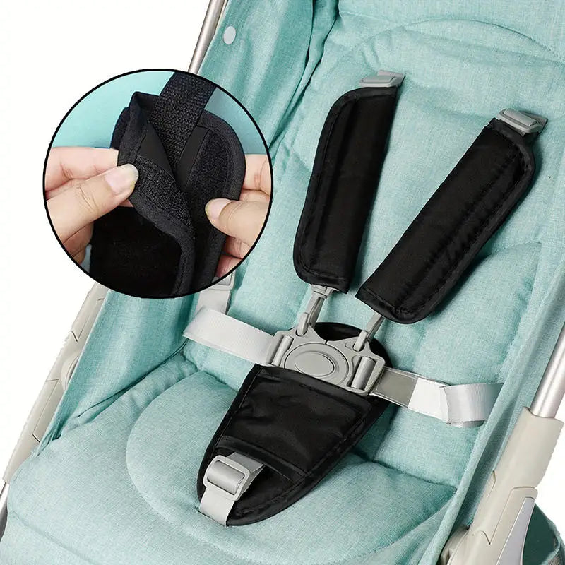 Black fabric cushion covers for baby stroller and car seat belts shown on a light green fabric background