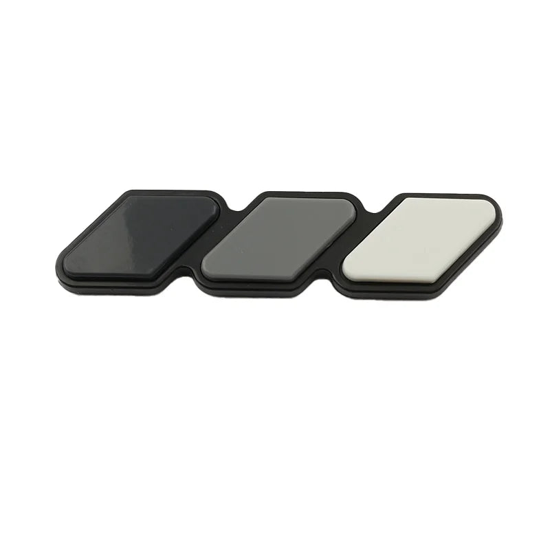 A set of three colored grille emblem stickers in black, gray, and white for Toyota trucks and SUVs