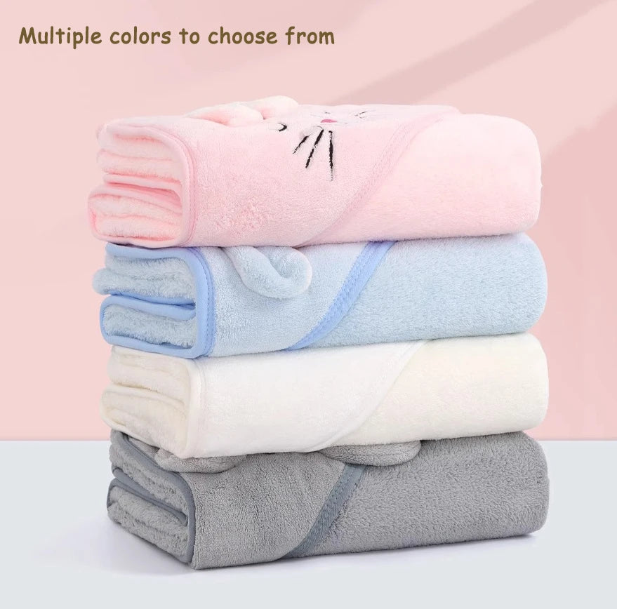 A stack of multiple colored, fuzzy hooded baby bathrobe towels with cartoon designs.