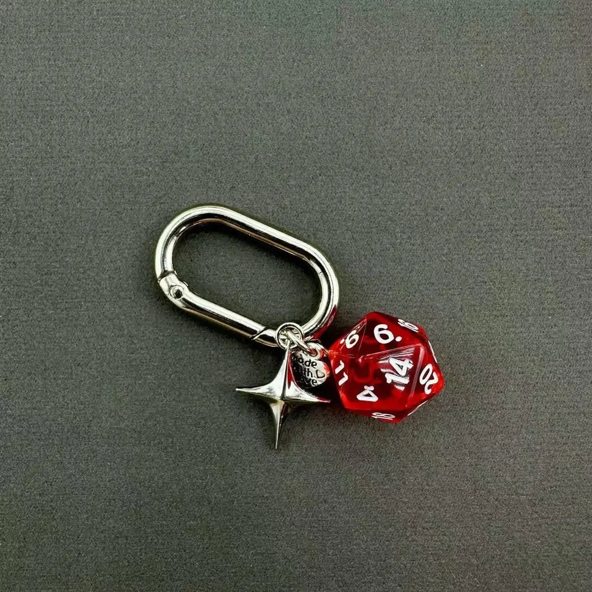 A silver heart-shaped keychain charm featuring a red dice with the number 14.