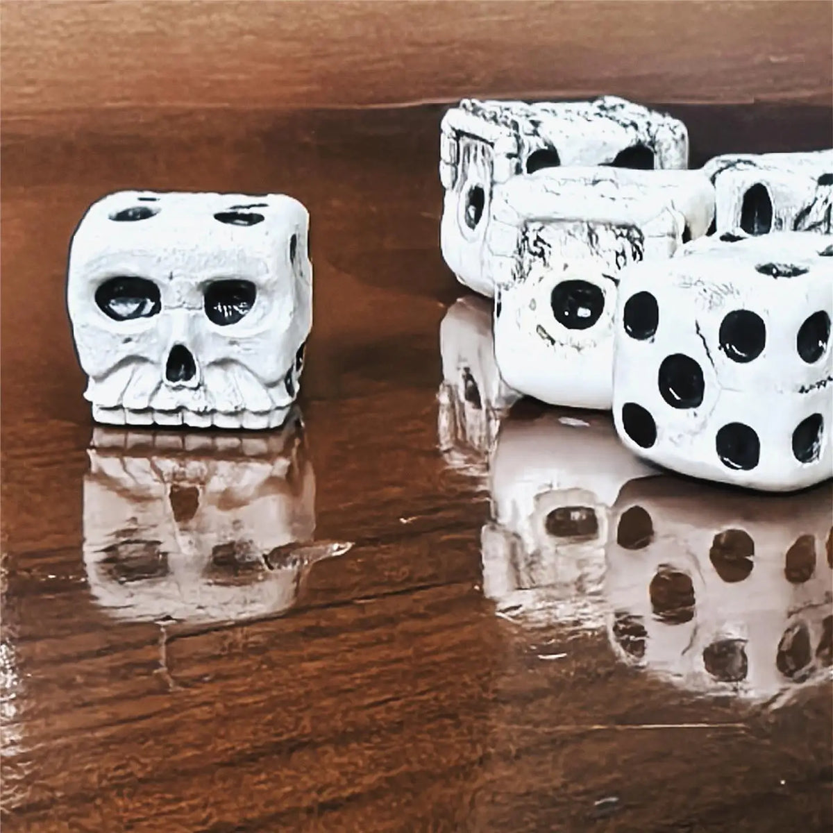 A set of white skull dice for tabletop games and Halloween, displayed on a dark wooden surface.