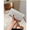 A hand holds an elegant patent leather clutch bag with a chain strap, showing the textured silver material.