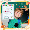 A young boy smiling while holding a colorful paper with stars and stickers, set against a green chalkboard background.