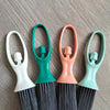 A set of compact mini brooms with black bristles and a green handle, shown against a gray background.