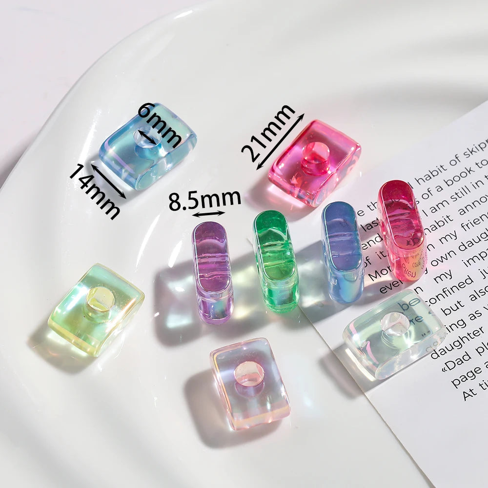 Various clear and colored acrylic alphabet beads of different sizes displayed on a white plate.