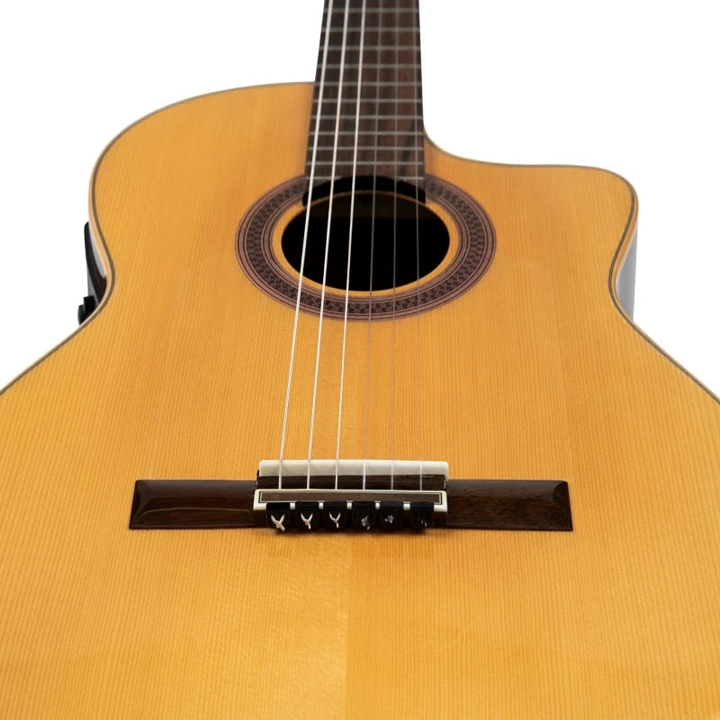 A close-up view of a yellow classical guitar showing the soundhole and bridge.