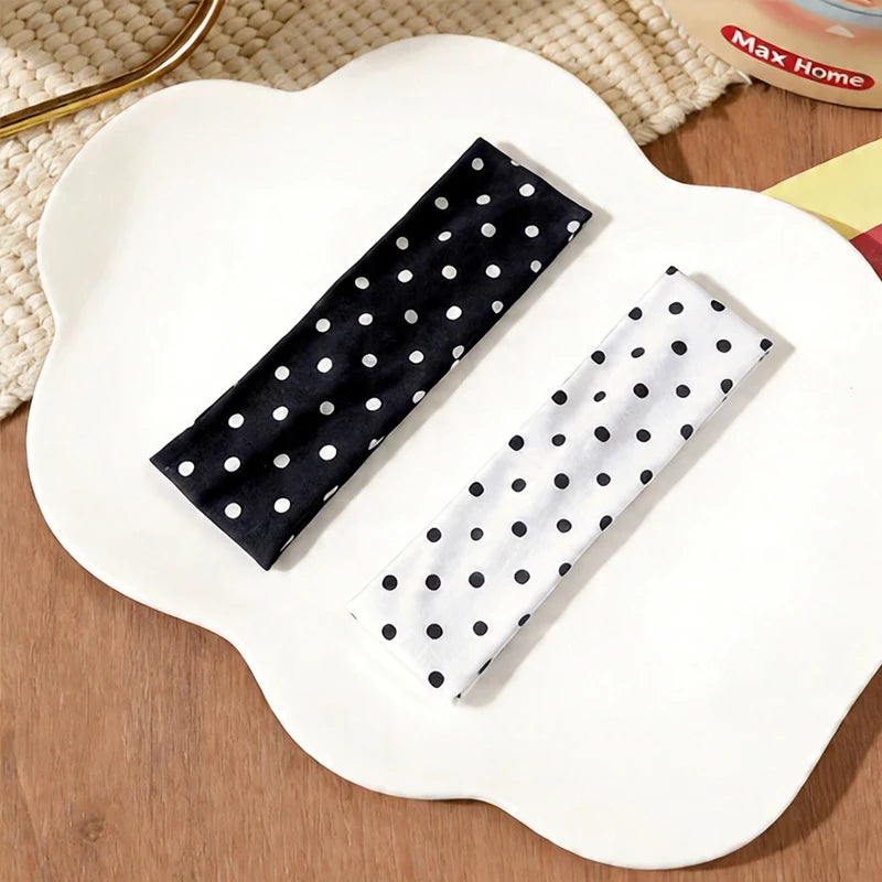 Deux bandeaux de tête à pois noir et blanc présentés sur une assiette blanche.