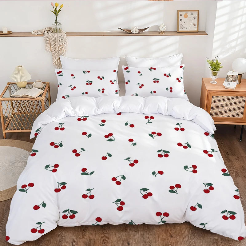 White duvet cover set with a red cherry print featuring scattered cherries on a light wood shelf.
