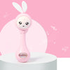 A pink musical rabbit rattle and teether toy is displayed on a white surface against a pink background.