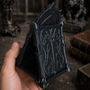 A hand holds a black gothic skull phone stand with intricate thorn details.