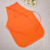 Orange non-woven fabric craft apron laid flat on a light gray fabric with a small white flower in the upper right corner.