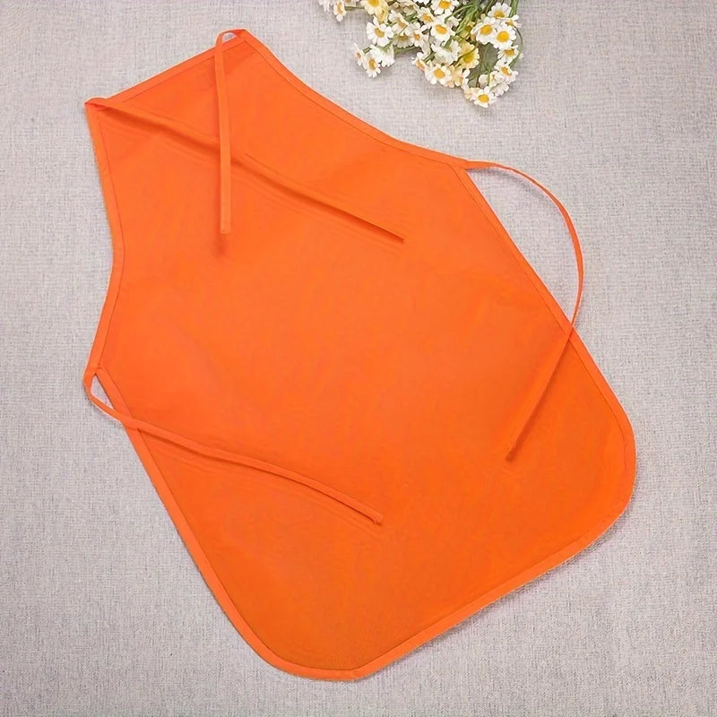 Orange non-woven fabric craft apron laid flat on a light gray fabric with a small white flower in the upper right corner.
