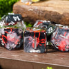 A set of black resin dice with red and white markings resting on a wooden surface.
