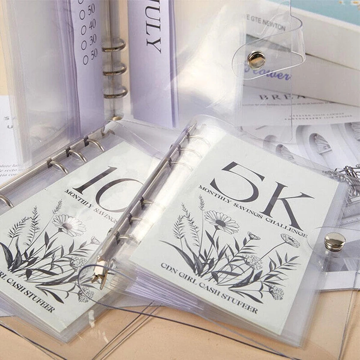 Durchsichtige Plastikhülle mit monatlicher Spar-Challenge-Klammer mit floralen Designs und Text.