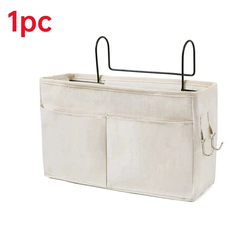 A beige hanging storage organizer with two cotton pockets and black hooks.