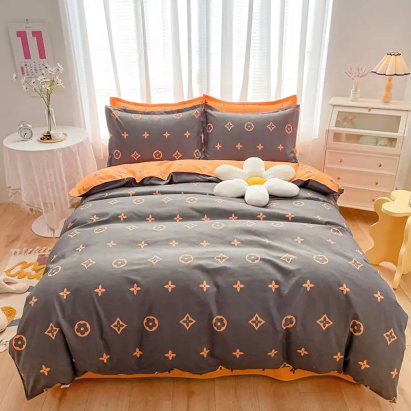 A gray bedding set with orange accents featuring a duvet cover, fitted sheet, and pillows on a bed.