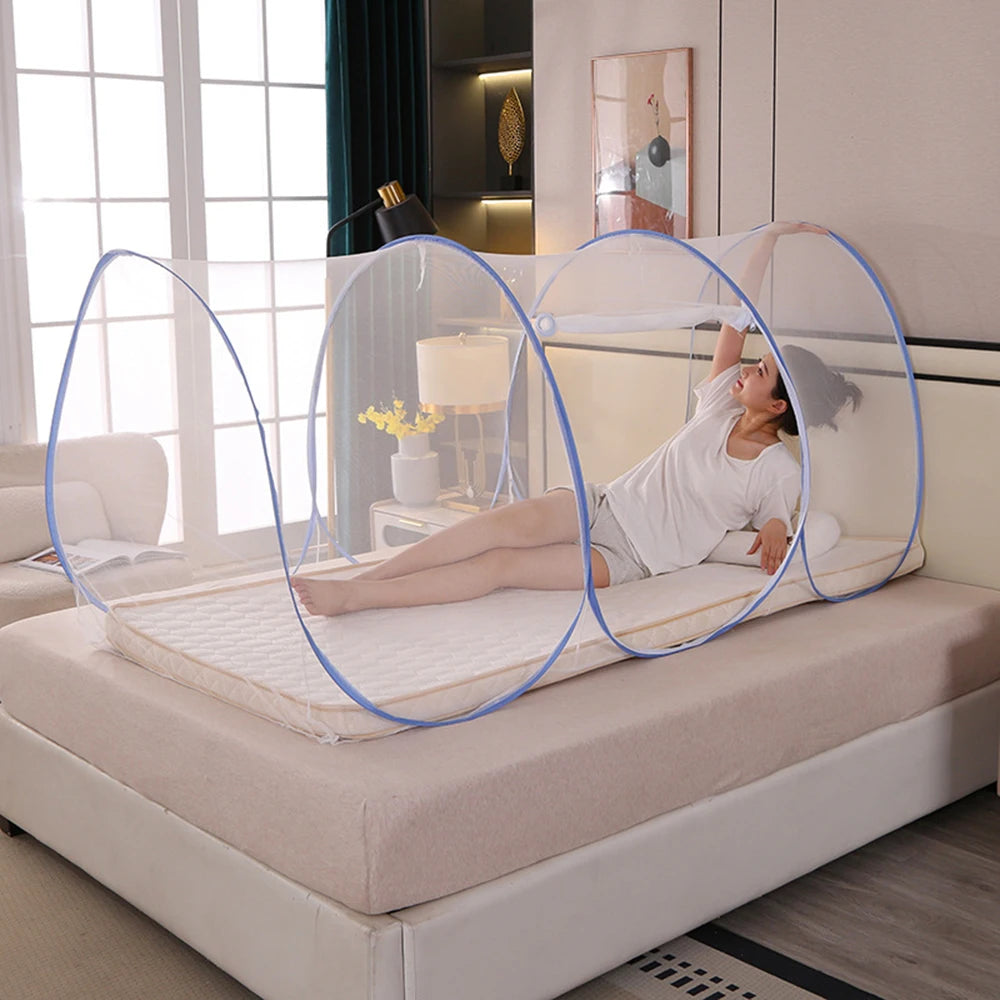 A person relaxing on a bed under a large mesh fly net canopy.