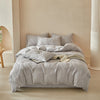 A light gray embossed leaf pattern microfiber duvet cover set displayed on a bed in a softly lit room.