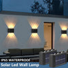 An IP65 waterproof solar LED wall lamp mounted on a white exterior wall, illuminating the area.