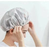 A person is putting on a disposable waterproof shower cap for bathing and hair care.