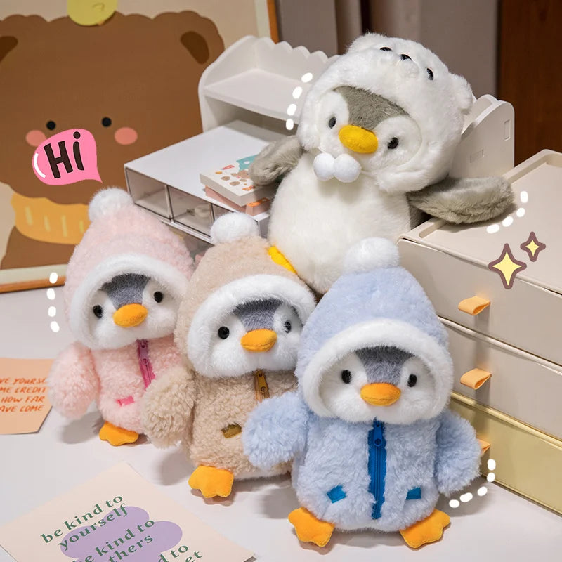 A fluffy white penguin plush toy wearing a hat sits next to other penguin toys on a white surface.
